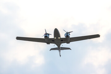 Small aircraft flying overhead against a cloudy sky during a calm day