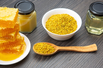Natural honey and bee pollen displayed on wooden table with jars and honeycomb