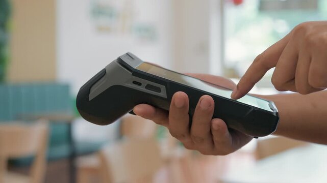 Close-up hand of a customer tapping credit card with a payment terminal or credit card machine at a cashier in a restaurant. cashless payment, card reader, electronic funds transfer