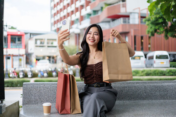 Young woman taking selfie with shopping bags in the city
