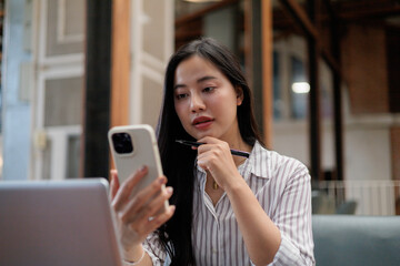 Focused businesswoman using smartphone and thinking in modern office