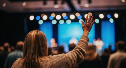 Woman raising hand in worship at a church service with bokeh lights and stage in background