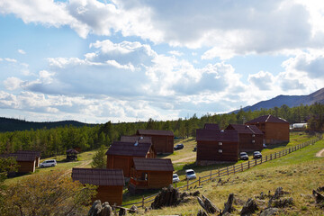 A tourist center with wooden houses in a rustic style against the backdrop of hills and trees.