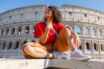 A joyful traveler stands proudly in front of the iconic Colosseum, capturing a moment that beautifully showcases a delightful blend of ancient history, stunning architecture, and modern style