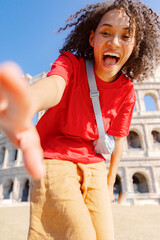 A young woman joyfully poses with a bright smile at the iconic Colosseum, capturing a special moment filled with happiness and adventure beneath the vast, clear blue sky on a sunny day