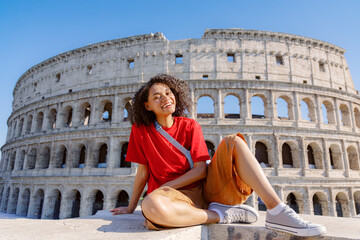 A very cheerful traveler poses happily in front of the iconic Colosseum in beautiful Rome, capturing the sheer joy of exploration and thrilling adventure during their memorable visit
