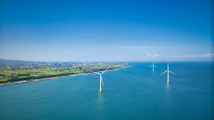 残暑の中の日本の富山県東部の海岸線で発電をしている洋上風力発電風車の様子