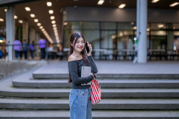 Fototapeta premium University student talking on phone holding tablet and bag