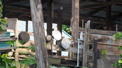 Rustic wooden shack architecture featuring weathered timber posts and rusty corrugated iron siding. Humble hanging aluminum kitchenware, including a colander and pots
