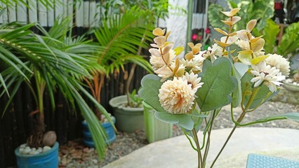 Close-Up of White Artificial Decorative Flowers with Green Leaves in a Home Garden