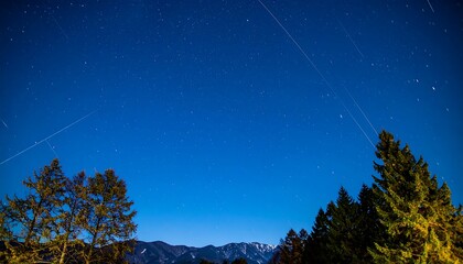 Naklejka premium Star trails over a mountain landscape at night