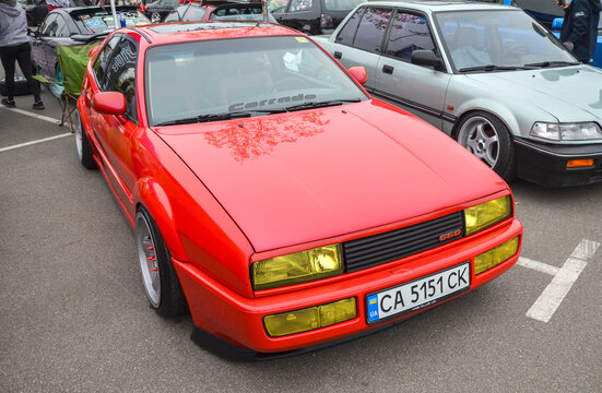Сustom red 1990 Volkswagen Corrado, sport compact coupe features lowered stance, aftermarket wheels, and yellow-tinted headlights, giving it distinct, modified look