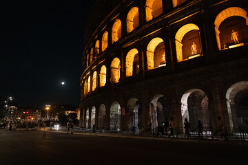 Roman Colosseum Illuminated at Night with Moon in Background