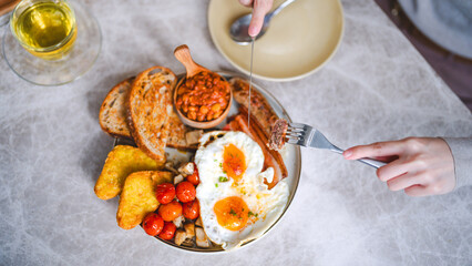 Eating english breakfast menu on marble table with tea fried eggs baked beans in tomato sauce and grilled bacon sausage tasty meal