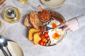 Eating english breakfast menu on marble table with tea fried eggs baked beans in tomato sauce and grilled bacon sausage tasty meal