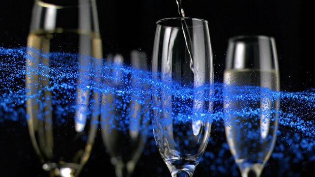 Droplet appearing above center flute causing pouring to fill glass while blue particles sweeping by