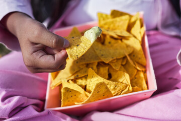 Girl holding nachos with guacamole in pink bowl