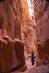 Tourist explores the Narrow Slot Canyon with its vibrant red rock formations