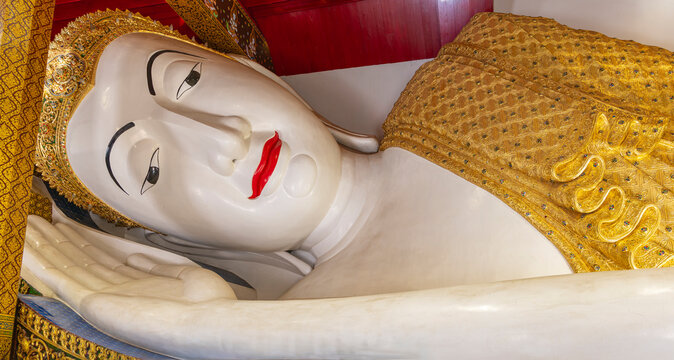 White reclining Buddha statue is wearing golden robewhite beautiful thai pattern.