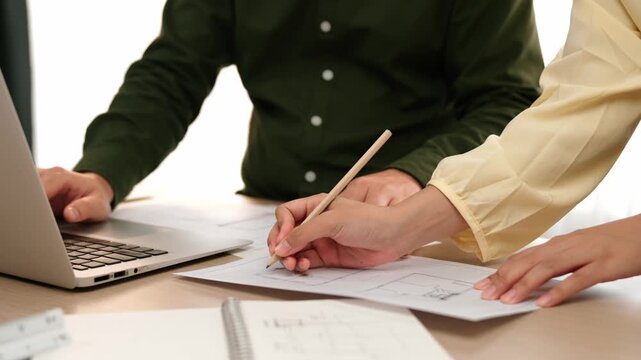 Architect and engineer compare hand writing draft with construction blueprint detail display in laptop for accurate design, measurement tool and plan on table at modern office. Closeup. Delineation.