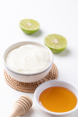 Yogurt, lime and honey on white background