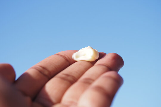 sunscreen cream on hand against blue sky backdrop