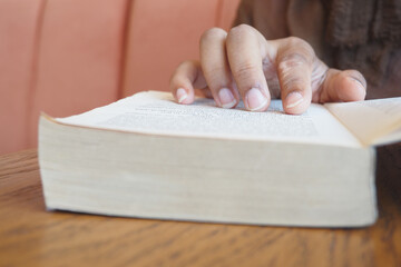 Person reading a book on a wooden table