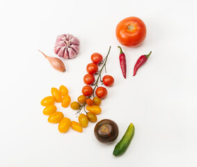 Tomatoes of different varieties, chili pepper, garlic, cucumber form a colorful composition on a white background. Flat lay. Harvest, Isolated