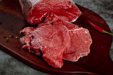 Fresh Raw Beef Steaks on Wooden Cutting Board with Spices Ready for Cooking