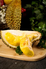 Golden durian fruit slices on wooden board displaying creamy flesh and spiky shell