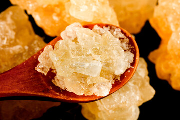 Large Rock Sugar Cubes on Wooden Spoon with Yellow Crystal Formations Background