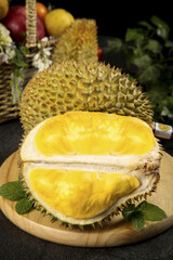 Fresh Golden Durian Fruit Cut Open Showing Yellow Flesh in Spiky Shell on Wooden Board