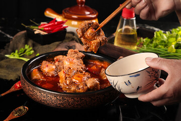 Spicy Oxtail Stew in Traditional Cast Iron Pot with Fresh Herbs and Cooking Ingredients