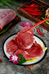 Fresh Raw Beef Slices Ready to Cook with Chopsticks and Vegetables on Rustic Table
