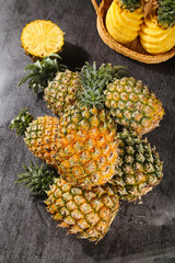Fresh Pineapples Whole and Sliced in Wicker Basket on Dark Stone Surface - Tropical Fruit Display