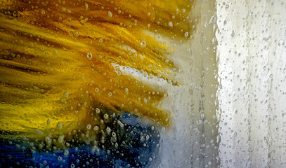 Bright colors mix as water sprays from a car wash machine, washing away dirt and grime from vehicles during a sunny day.