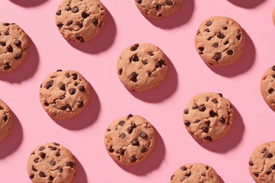 Flat lay top view of chocolate chip cookies arranged as circle on pink background - Powered by Adobe