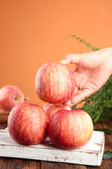 Fresh Red Fuji Apples from Luochuan Shandong China on Rustic Wooden Board with Hand Reaching