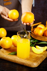 Fresh Orange Juice with Citrus Fruits and Peach on Wooden Board in Kitchen