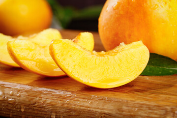 Fresh Golden Peach Slices on Wooden Board with Whole Fruits and Leaves