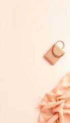 Sophisticated peach toned fashion accessories with a small handbag and draped scarf create a textured flat lay composition