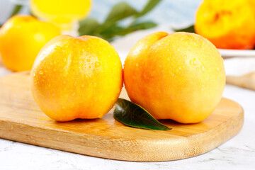 Fresh Yellow Summer Nectarines on Wooden Board with Water Drops and Green Leaves