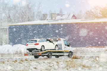 Tow truck carrying broken car in snow