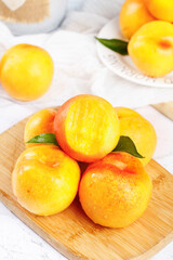 Fresh Yellow Peaches Cut in Half on Wooden Board Showing Juicy Flesh and Green Leaves