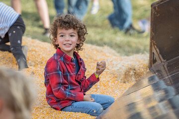 Smiling child sits in corn pit at Utah pumpkin patch