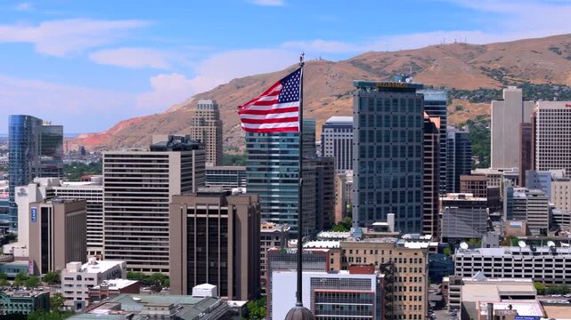 Salt Lake City 07.03.2025. Stunning aerial footage offers a view of Salt Lake City Utah skyline, highlighting its tall buildings and the iconic American flag, a symbol of pride and patriotism