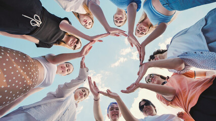 School friends united in a circle against a clear blue sky, showcasing their strong friendship and teamwork