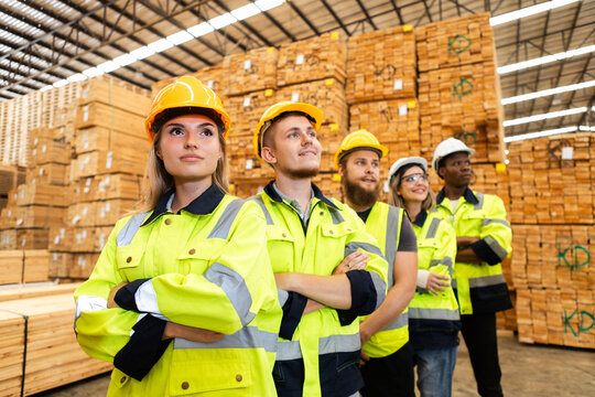 Confident team of diverse warehouse workers wearing safety uniform standing together in lumber storage facility, symbolizing teamwork, industrial workforce and safe work environments.
