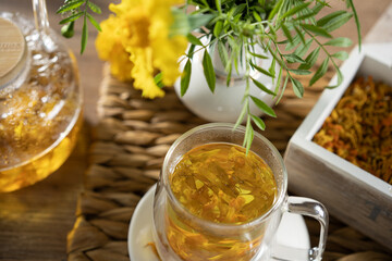 Herbal tea preparation with fresh ingredients and flowers on a wooden table
