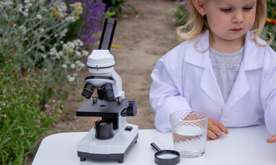 A little girl tests water using test tubes and a microscope